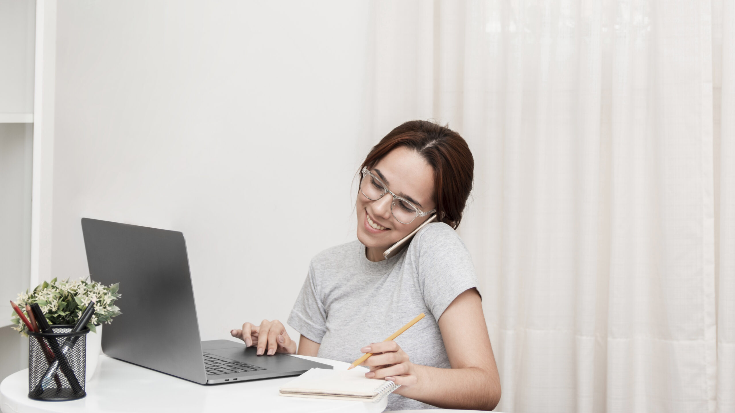 smiley woman talking phone while working laptop scaled